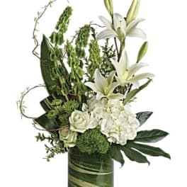 White lilies and roses arranged in a green glass vase