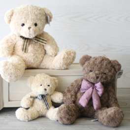 Three teddy bears with ribbon bows arranged on a wooden crate