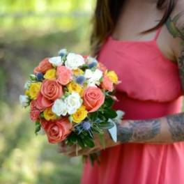 Woman holding a colorful bouquet of roses and small white flowers
