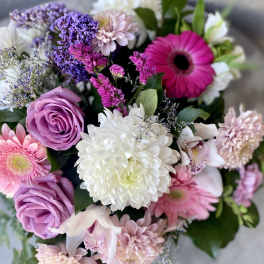 Mixed bouquet of pink gerbera daisies, lavender roses, white mums, and purple filler flowers.