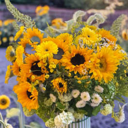 Bouquet of yellow sunflowers and white filler flowers in a striped vase