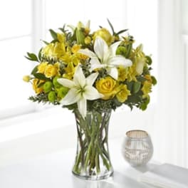 Yellow and white flower bouquet in a clear glass vase