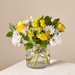 Yellow and white flowers in a clear glass vase