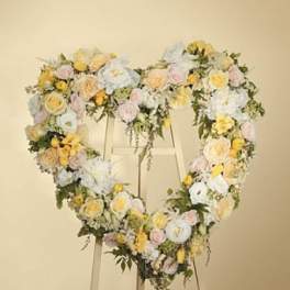 Heart-shaped floral wreath on an easel with pastel roses and white blooms