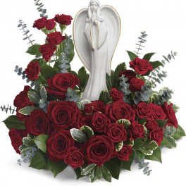 Red rose arrangement surrounding a white angel figurine