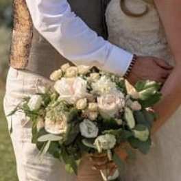 Bride and groom holding a small white and blush bouquet