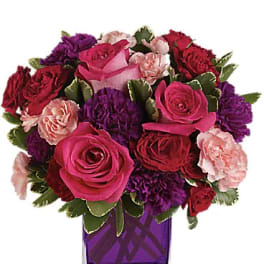 Pink, red, and purple roses in a purple glass vase