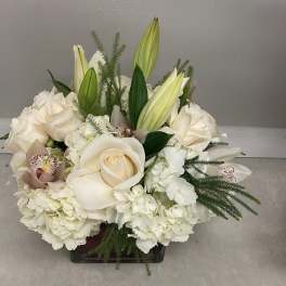 White roses and lilies arranged in a low square vase