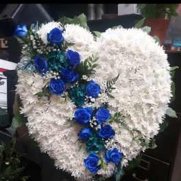 Heart-shaped white floral arrangement with blue roses