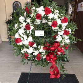 Large standing wreath of red roses and white flowers with a red ribbon