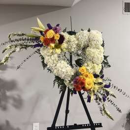 Large floral heart on an easel with white hydrangeas and colorful roses
