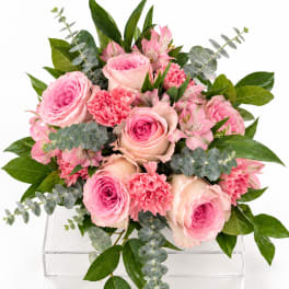 Pink roses and carnations arranged with alstroemeria in a clear acrylic vase