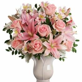 Pink roses and lilies arranged in a white vase