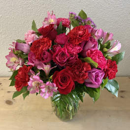 Bouquet of red and pink roses, carnations, and alstroemeria in a glass vase