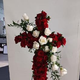 Cross-shaped floral arrangement of red and white roses on a stand