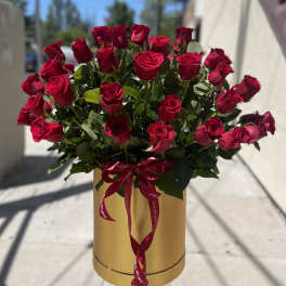 Bouquet of red roses in a gold hatbox with a red ribbon