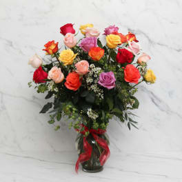 Colorful rose bouquet in a glass vase with a red ribbon