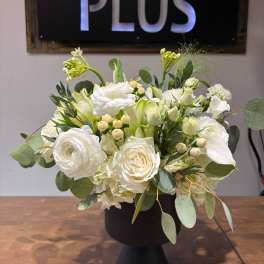White floral arrangement in a black pedestal vase