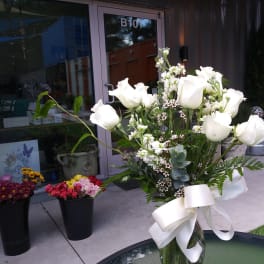 White rose bouquet in a glass vase with a white ribbon