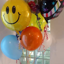 Cluster of colorful birthday balloons with a smiley face balloon
