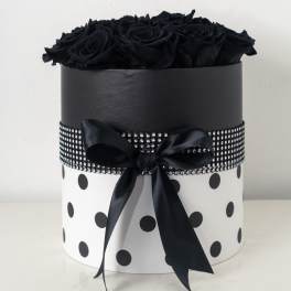 Black roses arranged in a round black and white polka dot hat box with rhinestone band and satin bow.