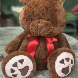 Brown plush teddy bear with a red ribbon bow