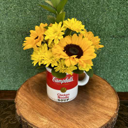 Yellow flowers arranged in a Campbell's soup mug