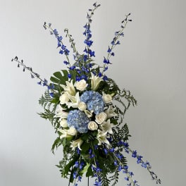 Tall floral spray with blue and white flowers on a stand