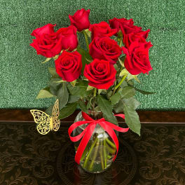 Red roses in a clear glass vase with a red ribbon