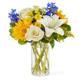 Bouquet of white lilies, roses, and yellow flowers in a glass vase