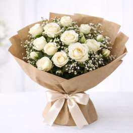 Bouquet of white roses wrapped in brown paper with a satin ribbon