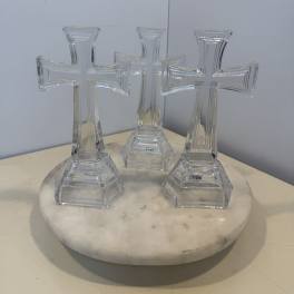 Three clear glass cross-shaped ornaments on a round white base