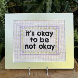 Framed cross-stitch sign with the words "it's okay to be not okay"