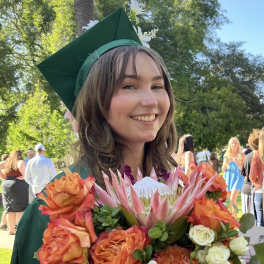Graduate holding a bouquet of orange and white flowers