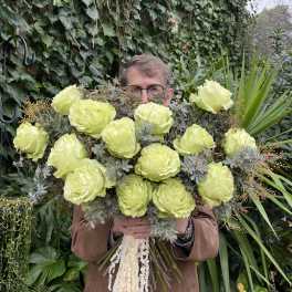 Person holding a large bouquet of pale green roses