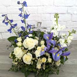White roses and purple irises arranged around a clear glass cross