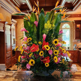 Large tropical floral arrangement with sunflowers, pink blooms, and bird-of-paradise