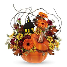 Pumpkin-shaped floral arrangement with orange and yellow flowers and a small house decoration