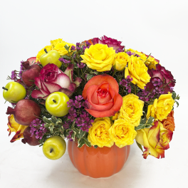 Pumpkin-shaped vase with yellow and coral roses and decorative fruit accents