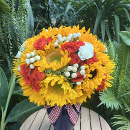 Sunflower and red rose bouquet in a dark vase with a gingham ribbon