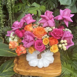 Bright mixed rose arrangement in a white pumpkin vase