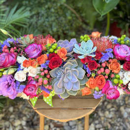 Colorful floral arrangement with roses and succulents in a wooden container