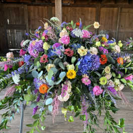 Large colorful floral arrangement with mixed blooms and trailing greenery