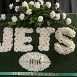 White floral letters on a green board with a football shape below