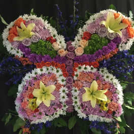 Butterfly-shaped floral arrangement with lilies, roses, and daisies