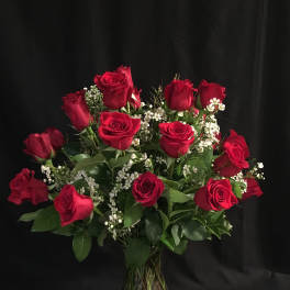 Bouquet of red roses with white filler flowers in a glass vase