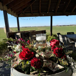 Red and white floral centerpiece with a glass candle on a barrel