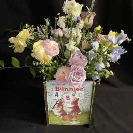 Pastel flower arrangement in a book-shaped container with bunny artwork
