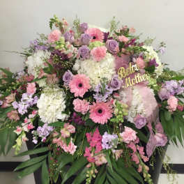 Large pastel floral arrangement with pink and lavender blooms in a black container