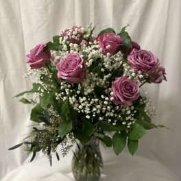 Bouquet of lavender roses and white baby's breath in a glass vase